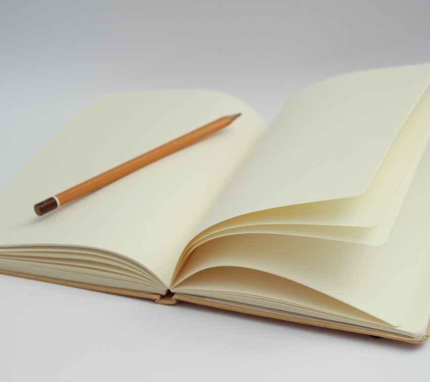 white notebook and yellow pencil